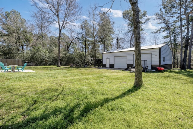 view of yard with a detached garage, a fire pit, an outdoor structure, and fence