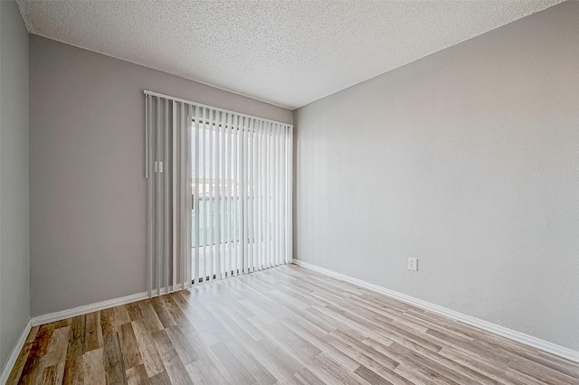 spare room with a textured ceiling, baseboards, and wood finished floors