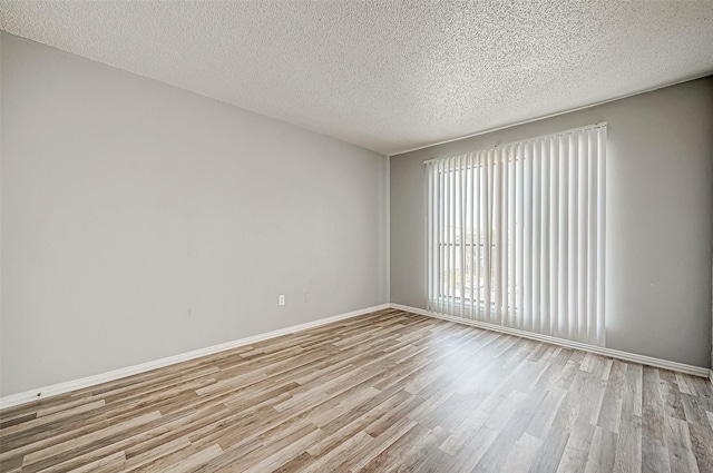 unfurnished room with light wood-style flooring, baseboards, and a textured ceiling