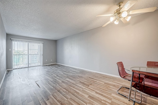 interior space with ceiling fan, light wood finished floors, a textured ceiling, and baseboards