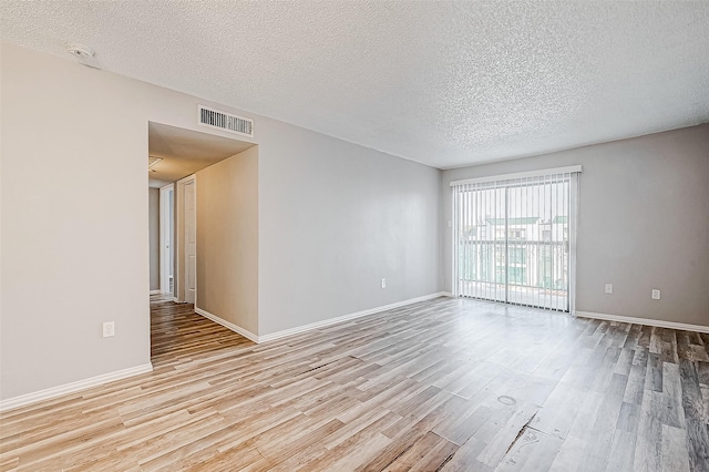 spare room featuring light wood-type flooring, visible vents, and baseboards