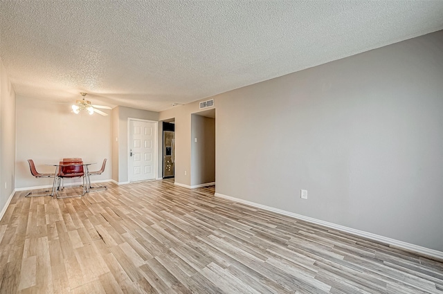 unfurnished room featuring a textured ceiling, ceiling fan, visible vents, baseboards, and light wood-type flooring