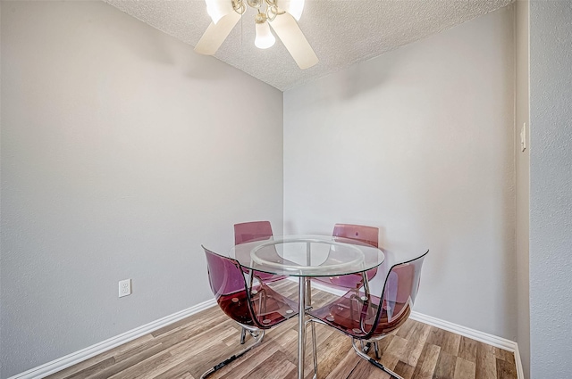 dining room with a textured ceiling, baseboards, and wood finished floors