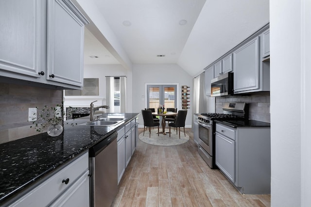 kitchen featuring stainless steel appliances, gray cabinets, a sink, and decorative backsplash