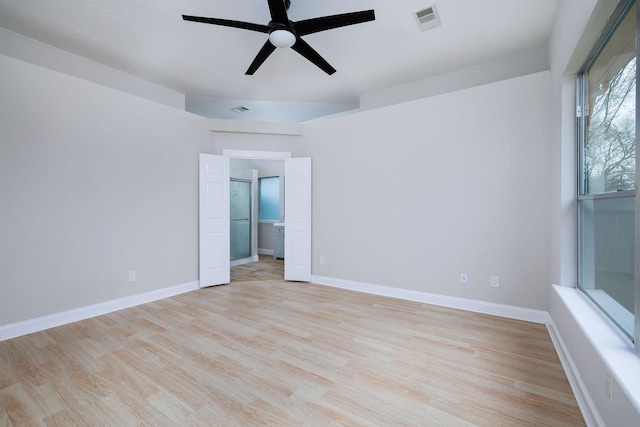 empty room with light wood finished floors, a ceiling fan, visible vents, and baseboards