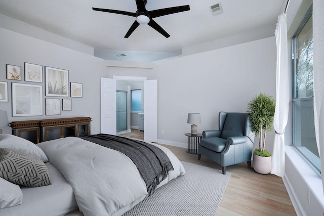 bedroom with ceiling fan, connected bathroom, light wood-style flooring, visible vents, and baseboards