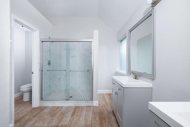 full bathroom featuring a marble finish shower, toilet, lofted ceiling, wood finished floors, and vanity