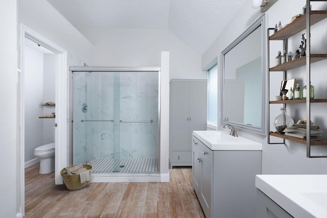 bathroom with lofted ceiling, a marble finish shower, wood finished floors, and vanity