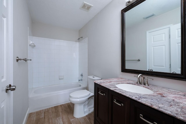 bathroom with visible vents, toilet, wood finished floors, vanity, and washtub / shower combination