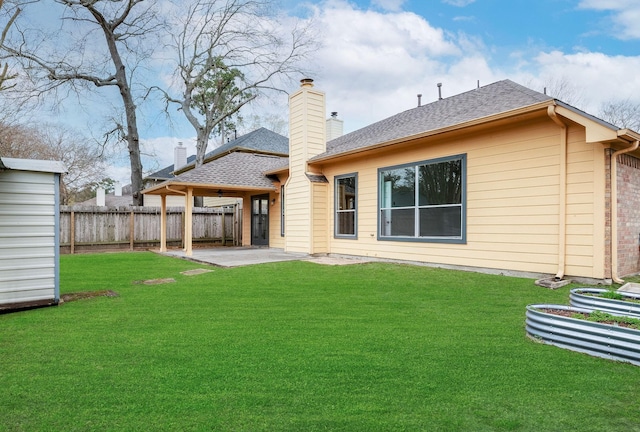 rear view of property with brick siding, a shingled roof, a lawn, a patio area, and fence