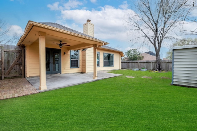 back of house with a lawn, ceiling fan, a chimney, fence, and a patio area