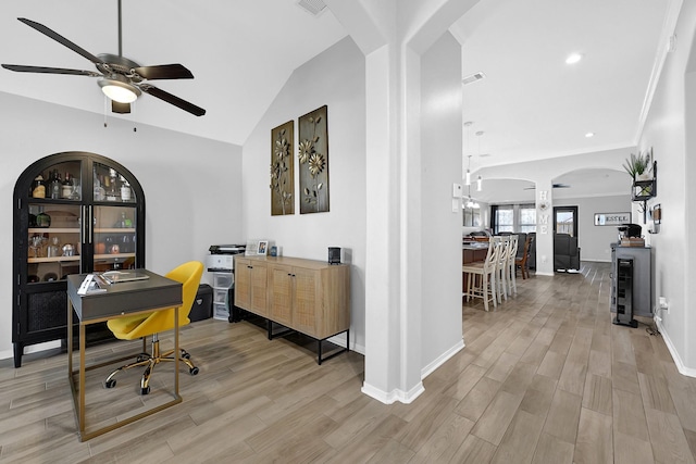 home office featuring visible vents, light wood-style flooring, arched walkways, lofted ceiling, and ceiling fan