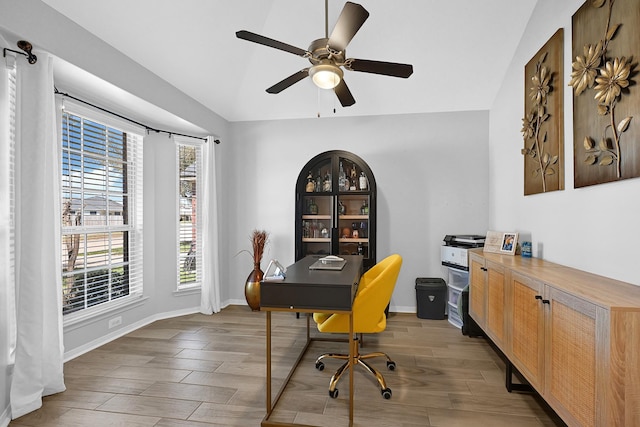 home office with vaulted ceiling, wood finished floors, baseboards, and ceiling fan