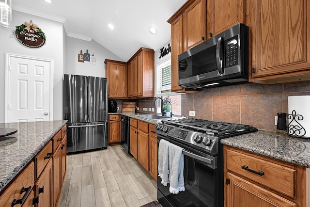 kitchen featuring brown cabinets, a sink, appliances with stainless steel finishes, crown molding, and tasteful backsplash