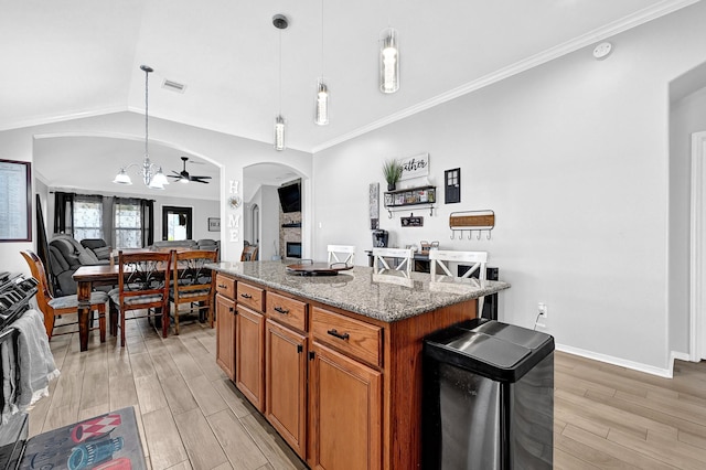 kitchen featuring a kitchen island, arched walkways, vaulted ceiling, light wood-style floors, and a notable chandelier