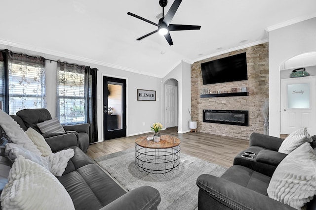 living area featuring crown molding, vaulted ceiling, wood finished floors, arched walkways, and a ceiling fan