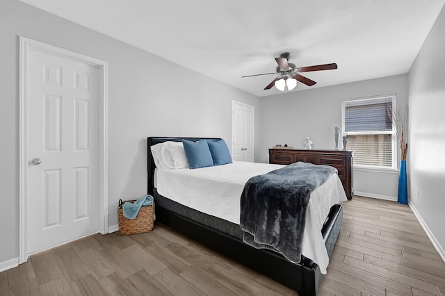 bedroom with a closet, baseboards, wood finished floors, and a ceiling fan