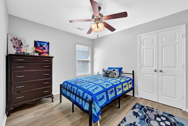 bedroom with visible vents, a closet, light wood finished floors, baseboards, and ceiling fan