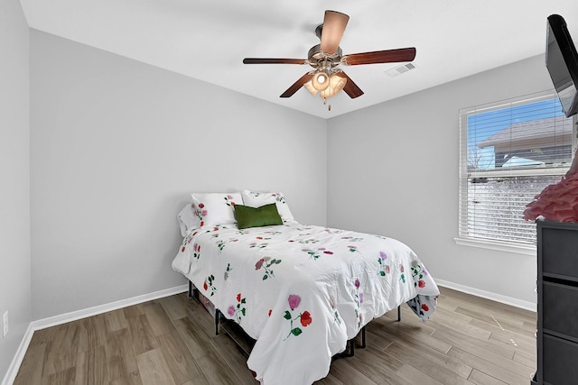 bedroom featuring visible vents, ceiling fan, baseboards, and wood finished floors