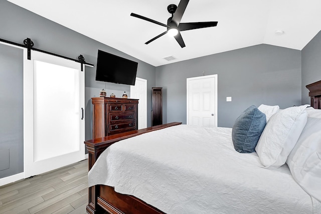 bedroom with visible vents, a ceiling fan, a barn door, light wood finished floors, and lofted ceiling