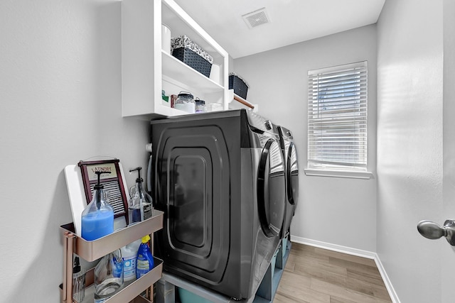 laundry area featuring visible vents, wood finished floors, separate washer and dryer, baseboards, and laundry area