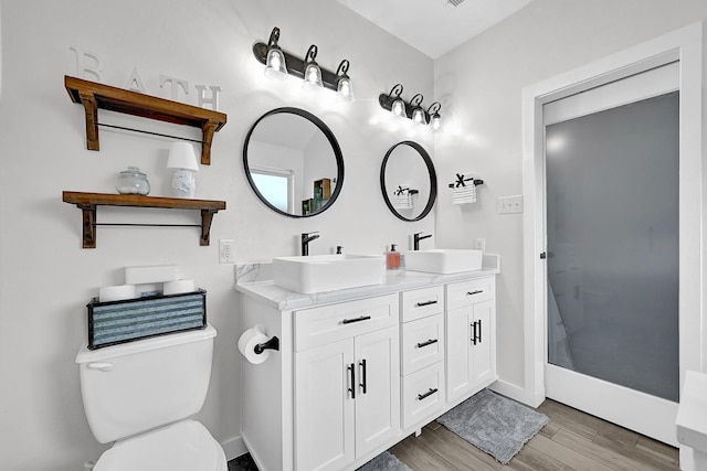 full bathroom featuring double vanity, toilet, wood finished floors, and a sink