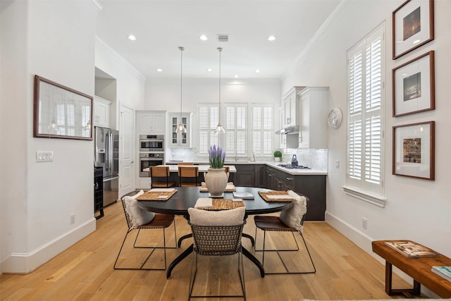 dining area with visible vents, baseboards, ornamental molding, and light wood finished floors