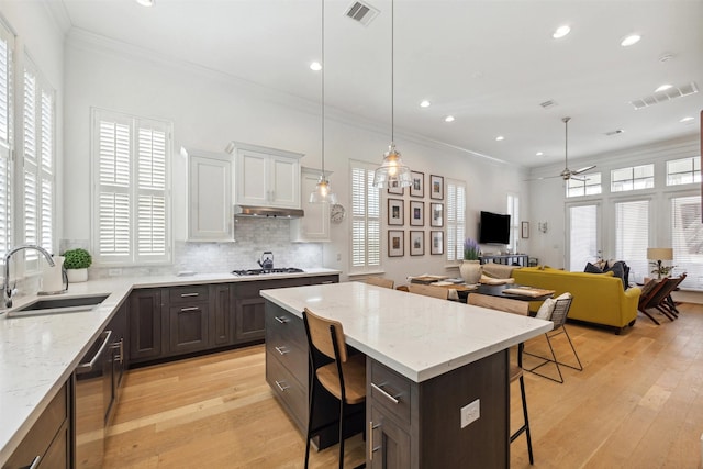 kitchen featuring visible vents, a kitchen breakfast bar, gas cooktop, and a sink