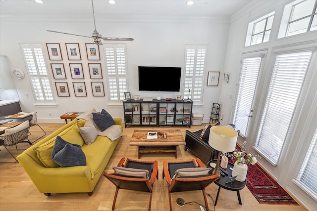 living room with a wealth of natural light, wood finished floors, a ceiling fan, and ornamental molding