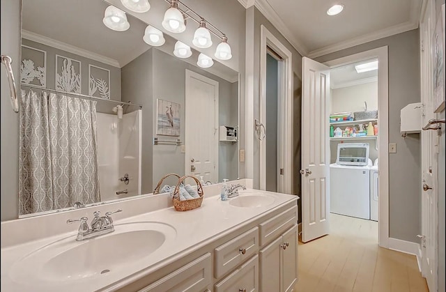 bathroom with double vanity, crown molding, a sink, and washing machine and clothes dryer