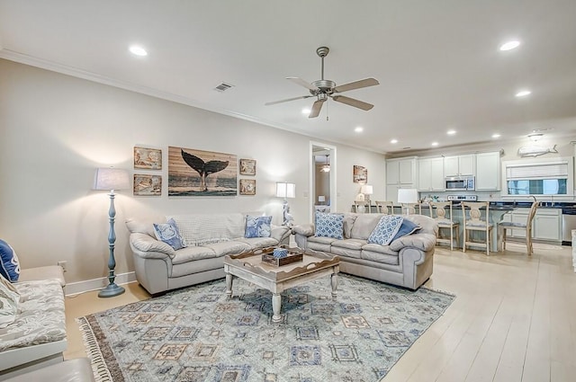 living room with light wood-style flooring, visible vents, crown molding, and recessed lighting