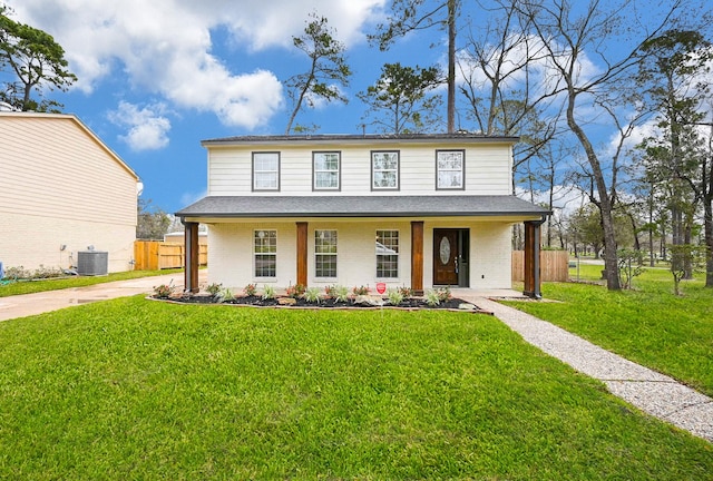 view of front facade with central AC, a front lawn, fence, and brick siding