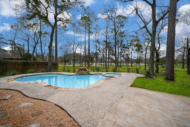 view of swimming pool with a fenced backyard, a pool with connected hot tub, a lawn, and a patio