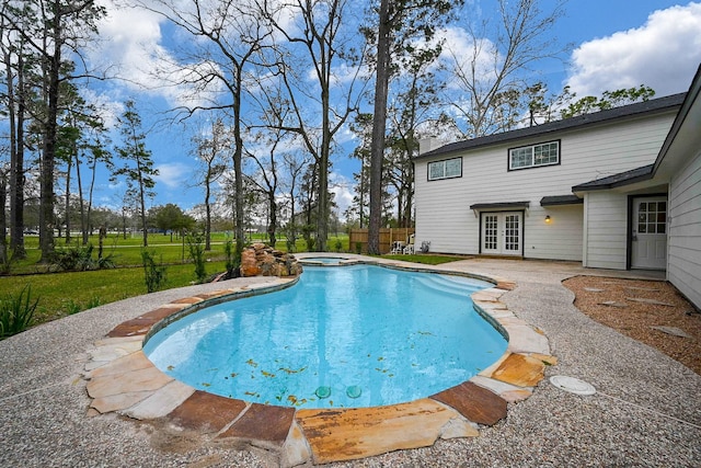 view of pool featuring a pool with connected hot tub, french doors, fence, and a patio