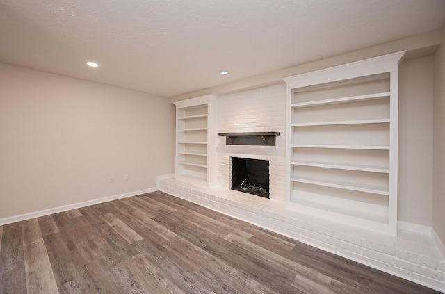 unfurnished living room with baseboards, wood finished floors, a textured ceiling, a fireplace, and recessed lighting