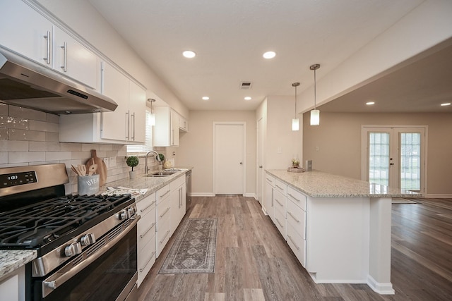 kitchen with light wood finished floors, appliances with stainless steel finishes, a sink, a peninsula, and under cabinet range hood