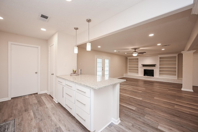 kitchen featuring french doors, a brick fireplace, wood finished floors, and visible vents