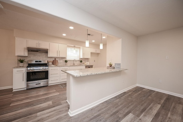 kitchen featuring dark wood-style flooring, decorative backsplash, gas stove, a sink, and under cabinet range hood