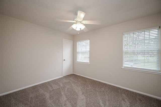 carpeted spare room featuring ceiling fan and baseboards