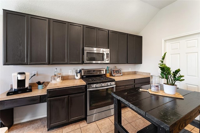 kitchen with lofted ceiling, light tile patterned floors, appliances with stainless steel finishes, and light countertops