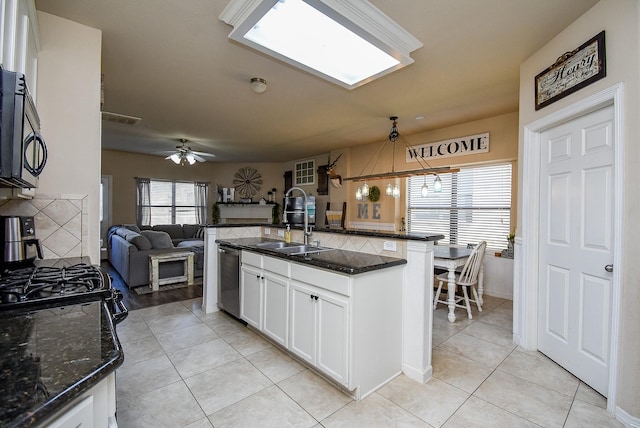 kitchen with stainless steel dishwasher, open floor plan, white cabinetry, a sink, and black microwave