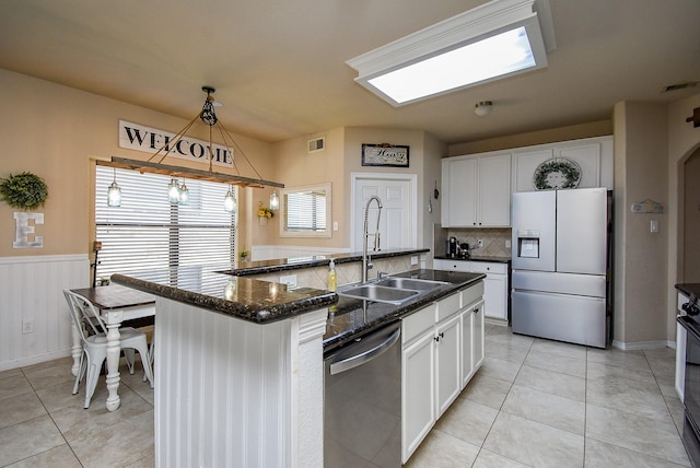 kitchen with visible vents, a wainscoted wall, stainless steel appliances, white cabinetry, and a sink