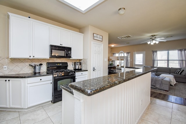 kitchen with light tile patterned flooring, visible vents, open floor plan, dark stone counters, and black appliances