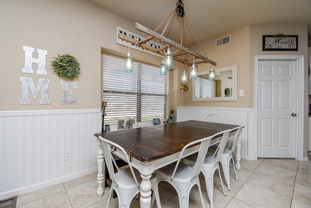 dining area featuring a wainscoted wall, visible vents, and light tile patterned flooring