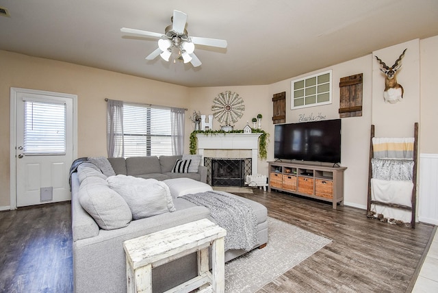 living room featuring a ceiling fan, visible vents, wood finished floors, and a tile fireplace