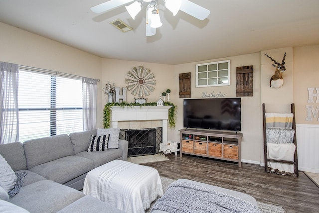 living room with visible vents, wainscoting, ceiling fan, wood finished floors, and a fireplace