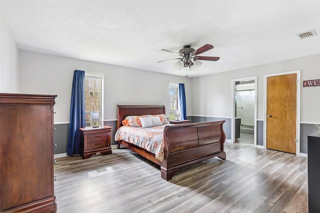 bedroom featuring a ceiling fan, wood finished floors, visible vents, and baseboards