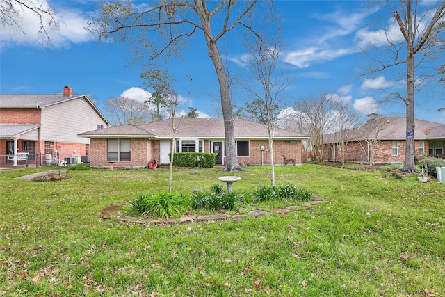 rear view of property featuring brick siding and a lawn