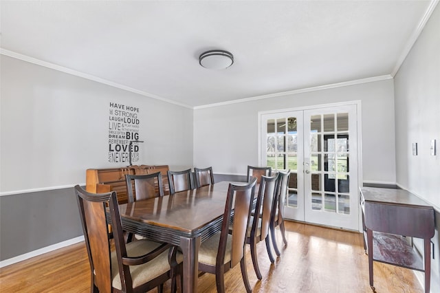 dining area with ornamental molding, french doors, baseboards, and light wood-style floors