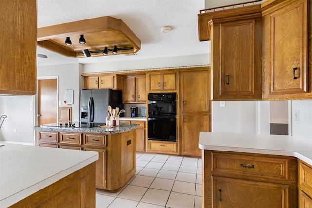 kitchen featuring light tile patterned floors, black appliances, brown cabinetry, and a kitchen island